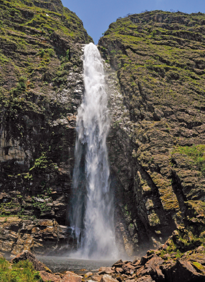 Imagem: Fotografia. Queda de água em cachoeira de uma montanha. Fim da imagem.