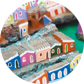 Imagem: Fotografia. Maquetes de casinhas coloridas lado a lado. Fim da imagem.