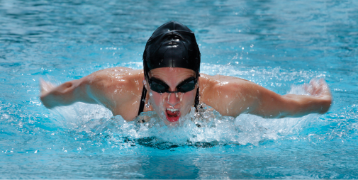 Imagem: Fotografia. Mulher de touca e óculos aquático nadando. Fim da imagem.