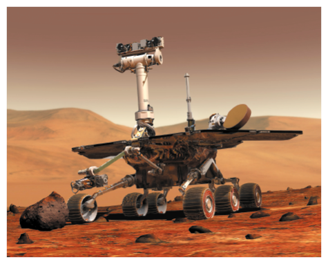 Imagem: Fotografia. Robô com placas e rodinhas sobre terra desértica vermelha em Marte. Fim da imagem.