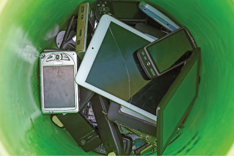 Imagem: Fotografia. Lixo eletrônico. Lata com celulares, tablets e outros aparelhos eletrônicos. Fim da imagem.