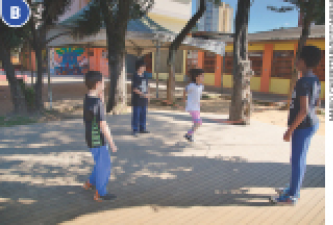 Imagem: Fotografia B. Crianças em um pátio com árvores. Ao fundo, a escola. Fim da imagem.