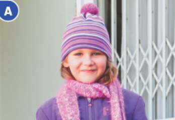 Imagem: Fotografia A. Menina com gorro, cachecol e blusa rosa e roxo está sorrindo. Fim da imagem.