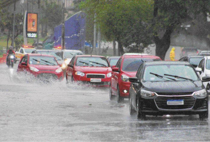 Imagem: Fotografia. Carros andando em uma rua em e volta há chuva caindo.  Fim da imagem.