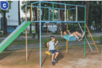 Imagem: Fotografia C. Dois meninos estão sentados em balanços. Acima deles há um suporte e nas laterais há uma escada e um escorregador. Ao fundo, árvores. Fim da imagem.