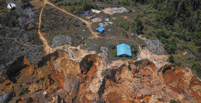 Imagem: Fotografia. Vista aérea de pequenas construções no topo de um morro com escavações. Ao lado, árvores e plantas. Fim da imagem.