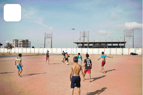 Imagem: Fotografia. Crianças jogando futebol em um campo.   Fim da imagem.