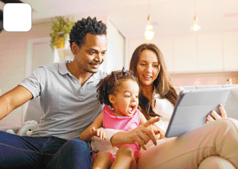 Imagem: Fotografia. Um casal e uma menina estão sentados e a mulher está segurando um tablet. A menina e o homem olham para o aparelho e sorriem.   Fim da imagem.