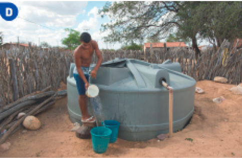 Imagem: Fotografia D. Um jovem está segurando um balde e jogando água dentro de outros baldes. Ao seu lado há uma caixa d’água gigante no chão.  Fim da imagem.