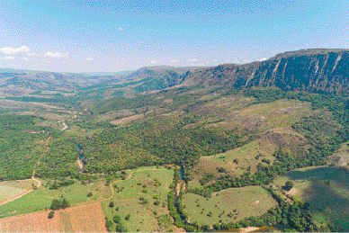 Imagem: Fotografia. Vista aérea de uma depressão coberta de vegetação.  Fim da imagem.