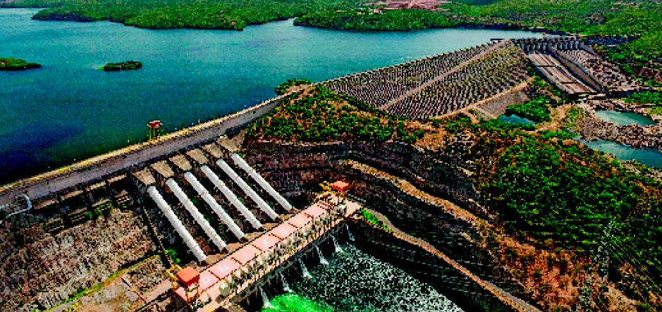 Imagem: Fotografia. Vista aérea de um lago extenso e ao lado há uma barragem. Fim da imagem.