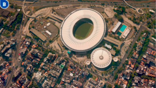 Imagem: Fotografia B. Vista aérea de um estádio circular e em volta há casas, ruas e árvores. Fim da imagem.