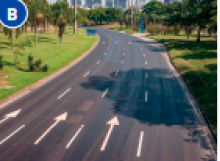 Imagem: Fotografia B. Avenida asfaltada com quatro vias. Nas laterais há árvores.  Fim da imagem.