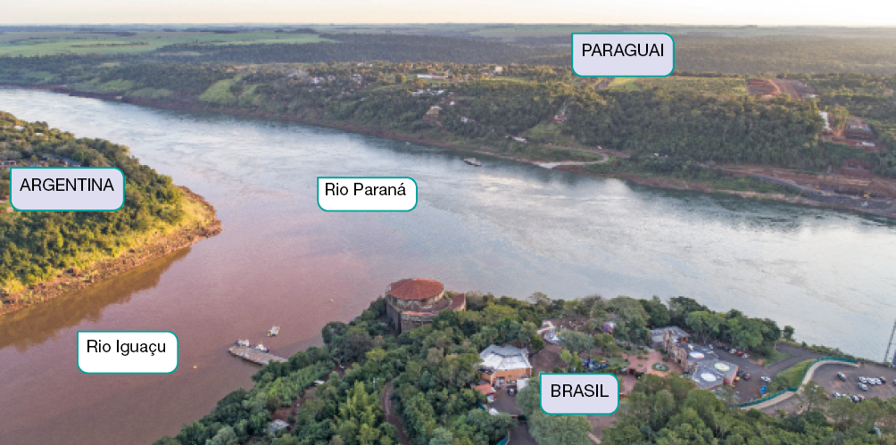 Imagem: Fotografia. Vista aérea do encontro de dois rios. À esquerda, a Argentina, ao lado, Rio Iguaçu e à direita, o Brasil. O Rio se encontra com o Rio Paraná acima e do outro lado da margem está o Paraguai.  Fim da imagem.