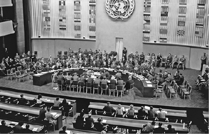 Imagem: Linha do tempo.  1948 – Declaração Universal dos Direitos Humanos.  Fotografia em preto e branco. Várias pessoas sentadas atrás de uma mesa curvada. Na frente há mais pessoas sentadas em mesas enfileiradas e observando.  LEGENDA: Reunião da Assembleia Geral da Organização das Nações Unidas (ONU), na cidade de Paris, na França, em 1948. FIM DA LEGENDA.   Fim da imagem.