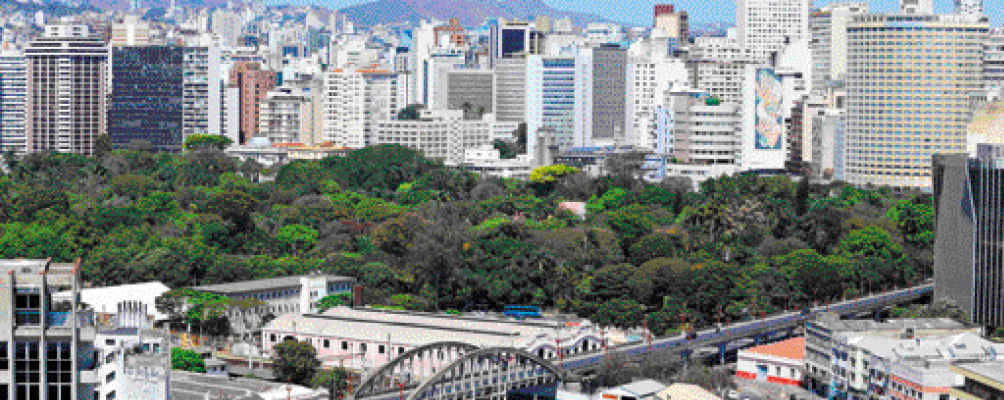 Imagem: Fotografia. Vista aérea de um parque com várias árvores. Ao redor há vários prédios e casas. Fim da imagem.