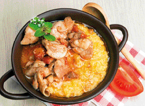 Imagem: Fotografia. Pedaços de frango e polenta dentro de uma panela.   Fim da imagem.