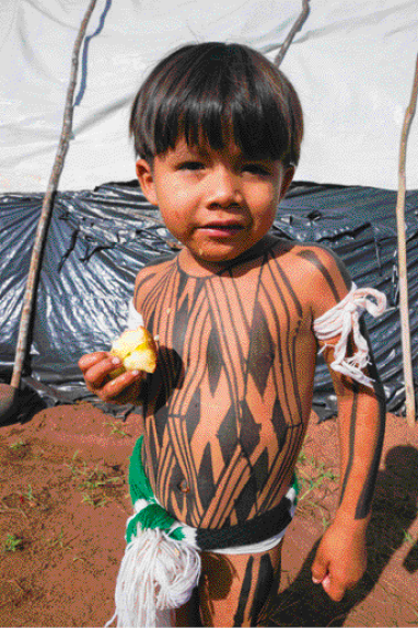 Imagem: Fotografia. Um menino indígena com pinturas pretas no corpo.  Fim da imagem.