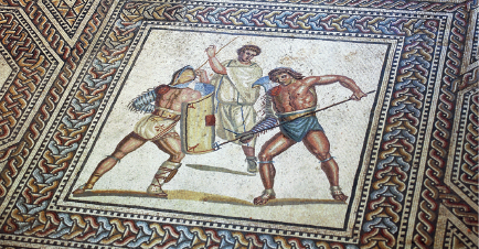 Imagem: Mosaico. À esquerda, um homem de costas segurando um escudo. Ao lado, outro homem segurando uma lança. Atrás, um homem com túnica branca olha na direção deles.  Fim da imagem.