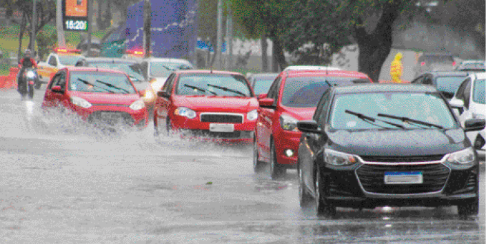 Imagem: Fotografia. Carros em uma rua durante a chuva. Eles espirram água para os lados.   Fim da imagem.