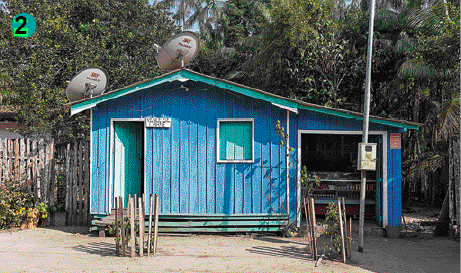 Imagem: Fotografia. Uma casa de madeira azul com porta e janela verde.  Fim da imagem.