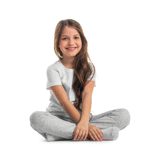 Imagem: Fotografia. Uma menina de cabelo castanho liso e longo. Ela está sorrindo e sentada de pernas cruzadas. Ela usa uma calça cinza e uma camiseta branca. Atrás dela, imagem do mapa mundi, com os continentes em verde e marrom e o oceano em azul. O Brasil está destacado.  Fim da imagem.