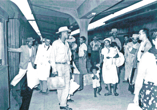 Imagem: Infográfico. Uma linha do tempo com imagens e informações. Até 1960. Ilustração de um homem e uma mulher com malas. Região Nordeste: As dificuldades de encontrar trabalho estavam entre as razões para a migração. Os migrantes nordestinos partiam preferencialmente para as regiões Sudeste e Norte, à procura de trabalho na indústria, na agricultura ou na mineração. Região Sul: Agricultores sulinos foram atraídos por novas áreas de cultivo na Região Centro-Oeste. Acima, fotografia antiga de homens, mulheres e crianças com malas em uma plataforma de trem. Che-gada de migrantes nordestinos ao município de São Paulo, no estado de São Paulo, cerca de 1960. Em 1970: Ilustração de um carrinho, cone de sinalização, martelo, enxada e capacete de proteção. Região Nordeste: Os migrantes nordestinos continuaram a liderar a migração para a Região Sudeste, principalmente para as grandes cidades. Eles estavam à procura de trabalho nas indústrias e na construção civil. Acima, fotografia da construção de um túnel, com trabalhadores no primeiro plano e andaimes perto da abertura do túnel. Construção da Rodovia dos Imigrantes, no estado de São Paulo, em 1974. Em 1980: ilustração de um boi. Regiões Sul e Sudeste: Os mi-grantes dessas regiões se deslocavam em direção a novas áreas agrícolas e de pecuária das regi-ões Centro-Oeste e Norte. Acima, fotografia de dois homens andando a cavalo na frente de uma boiada. Criação de gado no município de Miranda, no estado de Mato Grosso do Sul, em 1985. Até 2010: Região Sudeste: A partir de 1980, um grande número de migrantes que moravam na Região Sudeste, por exemplo, começou a retornar à Região Nordeste devido ao desenvolvimen-to da atividade industrial, de comércio e de turismo nessa região. Fotografia de dois homens na frente de uma máquina com rolos de tecidos. Indústria de tapetes de sisal no município de Va-lente, no estado da Bahia, em 2010. Ao lado, ilustração de um homem de capacete, camiseta vermelha e macacão amarelo. Ele segura uma lata de tinta e um pincel. A partir de 2010 a migra-ção de retorno, isto é, de migrantes que voltam ao seu local de origem, diminuiu, segundo o IB-GE, com um novo aumento a partir de 2020. Fim da imagem.