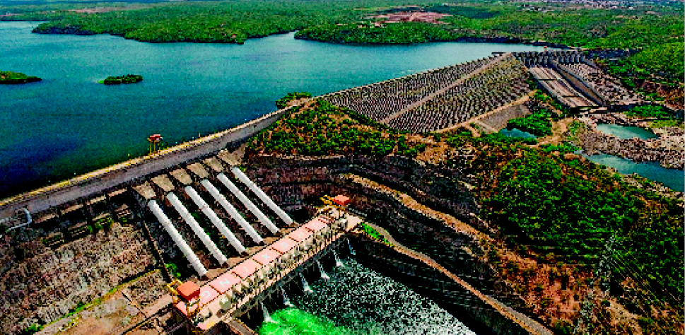 Imagem: Fotografia. Uma usina hidrelétrica em uma barragem.   Fim da imagem.