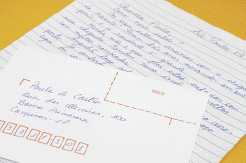 Imagem: Fotografia. Uma carta escrita em uma folha de caderno e um envelope preenchido em cima. Fim da imagem.