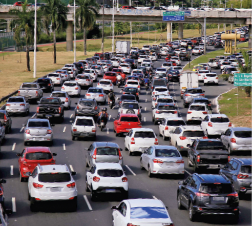 Imagem: Fotografia. Uma estrada com seis faixas, todas cheias de carro.  Fim da imagem.