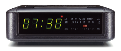 Imagem: Fotografia. Um relógio digital preto com visor amarelo que marca 07h30 e também apresenta estações de rádio no display. Fim da imagem.