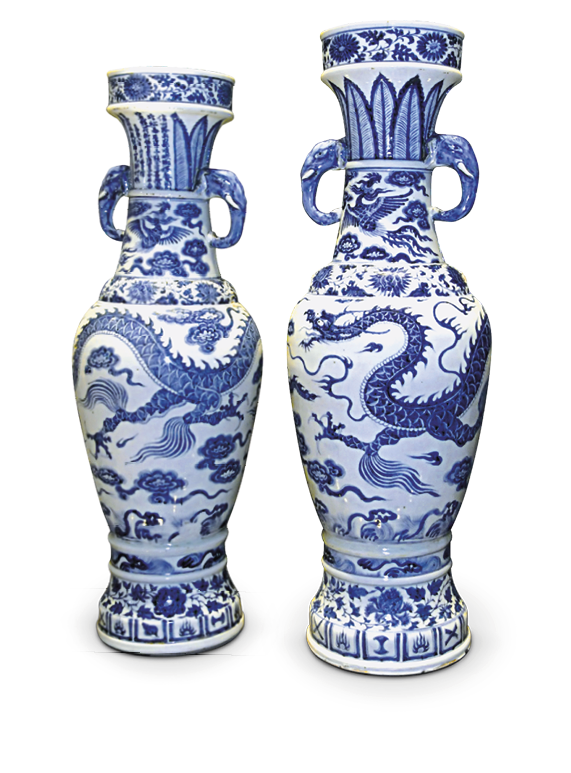 Imagem: Fotografia. Um par de vasos compridos com corpo ovalar e pequenos braços laterais. A superfície é branca com desenhos em azul com figuras como folhas e dragões. Fim da imagem.