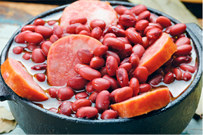 Imagem: Fotografia. Uma cumbuca com feijão e pedaços de carne.  Fim da imagem.