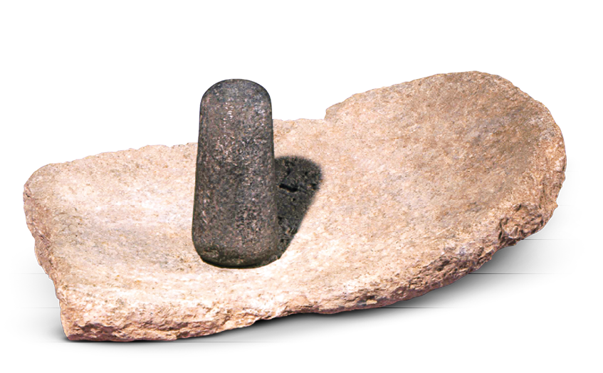 Imagem: Fotografia. Um pedaço de pedra largo e longo. Sobre ele há uma pedra menor, escura de formato cilíndrico. Fim da imagem.