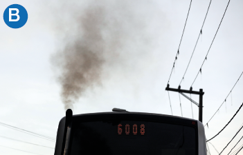 Imagem: B. Fotografia. Destaque da parte traseira de um ônibus que apresenta uma chaminé da qual sai densa fumaça. Fim da imagem.