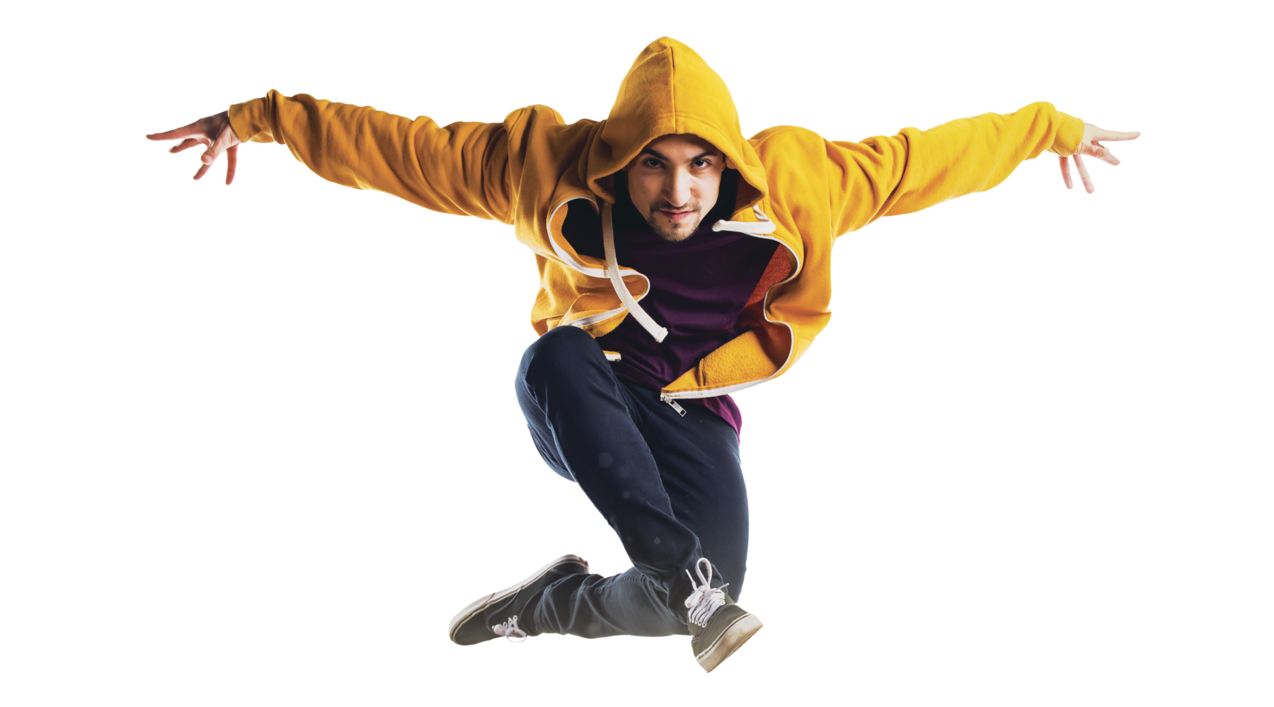 Fotografia. Rapaz  com casaco de capuz amarelo, calça jeans e tênis. Ele salta com os braços estendidos na horizontal e com as pernas flexionadas no ar.