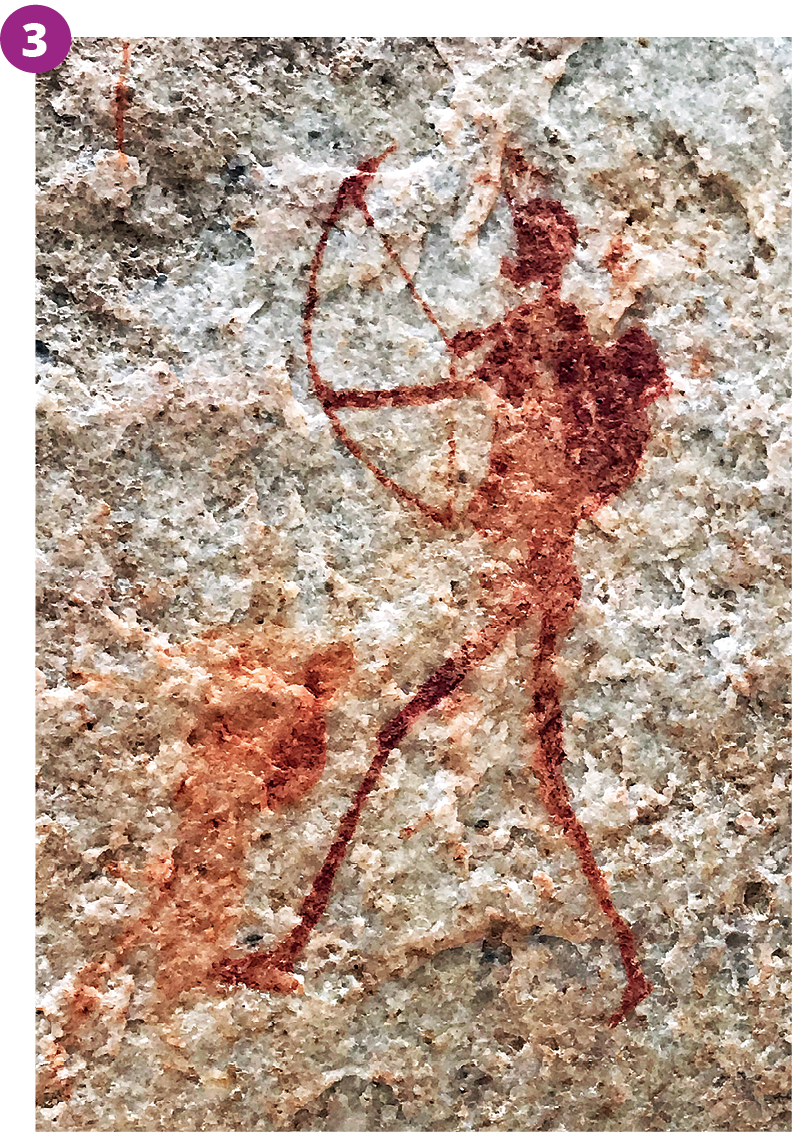 Fotografia 3. Pintura rupestre em tons de vermelho em uma parede de caverna mostrando uma silhueta humana segurando um arco e flecha apontado para frente.