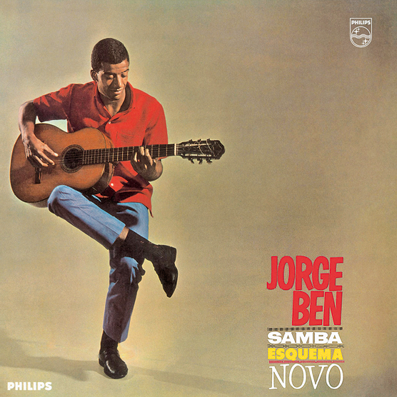 Fotografia. Capa de disco. Na parte inferior direita, o título: JORGE BEN – SAMBA ESQUEMA NOVO. À esquerda, o cantor, de cabelo preto curto, camisa vermelha, calça jeans, sapatos pretos sentado com as pernas cruzadas e segurando um violão no colo.