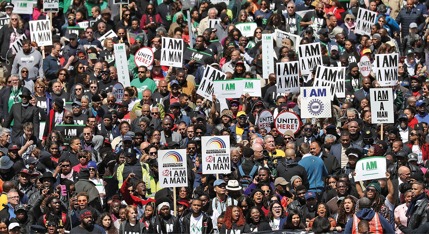 Fotografia. Pessoas reunidas em uma manifestação contra o racismo. Carregam cartazes com os dizeres: “I AM A MAN”.