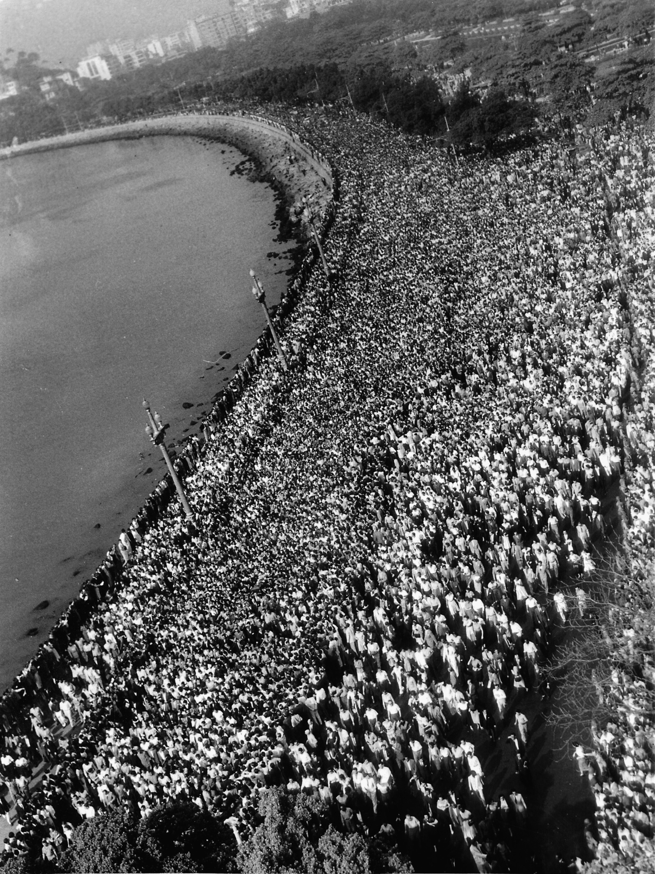 Fotografia em preto e branco. Vista aérea de uma multidão por toda a extensão da praia.
