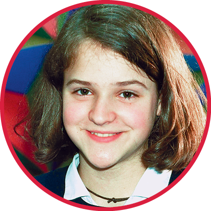 Fotografia. Zlata Filipović, menina sorridente de pele branca, cabelo castanho, liso e curto na altura do pescoço. Tem as bochechas rosadas.