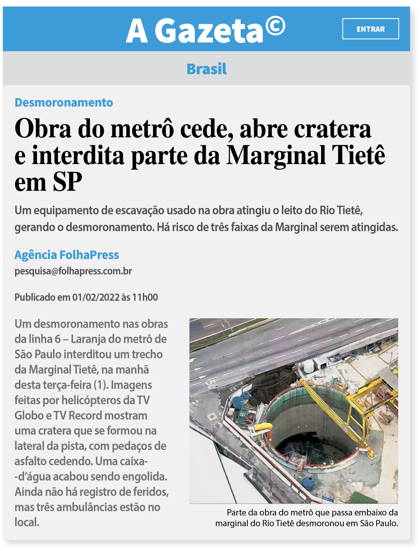 Reprodução de página de internet. Na parte superior o nome do site: A GAZETA©. Abaixo o conteúdo. Brasil. Desmoronamento. Obra do metrô cede, abre cratera e interdita parte da Marginal Tietê em SP. Um equipamento de escavação usado na obra atingiu o leito do Rio Tietê, gerando o desmoronamento. Há risco de três faixas da Marginal serem atingidas. Agência FolhaPress. <pesquisa@folhapress.com.br>. Publicado em 01/02/2022 às 11h00. Um desmoronamento nas obras da linha 6 – Laranja do metrô de São Paulo interditou um trecho da Marginal Tietê, na manhã desta terça-feira (1). Imagens feitas por helicópteros da TV Globo e TV Record mostram uma cratera que se formou na lateral da pista, com pedaços de asfalto cedendo. Uma caixa-d’água acabou sendo engolida. Ainda não há registro de feridos, mas três ambulâncias estão no local. Fotografia aérea de uma cratera no asfalto ao lado de um duto cilíndrico encaixado no subsolo.