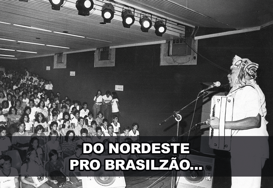 Fotografia em preto e branco. Luiz Gonzaga em uma apresentação no palco. Uma plateia sentada assiste. Texto: DO NORDESTE PRO BRASILZÃO.