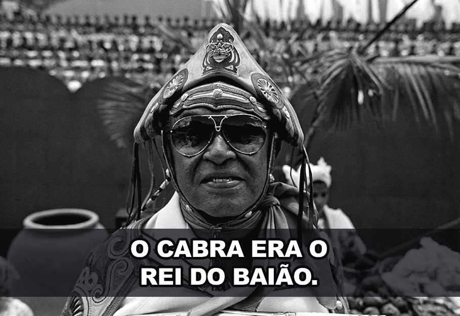 Fotografia em preto e branco. Luiz Gonzaga, com chapéu de cangaceiro e óculos escuros. Texto: O CABRA ERA O REI DO BAIÃO.