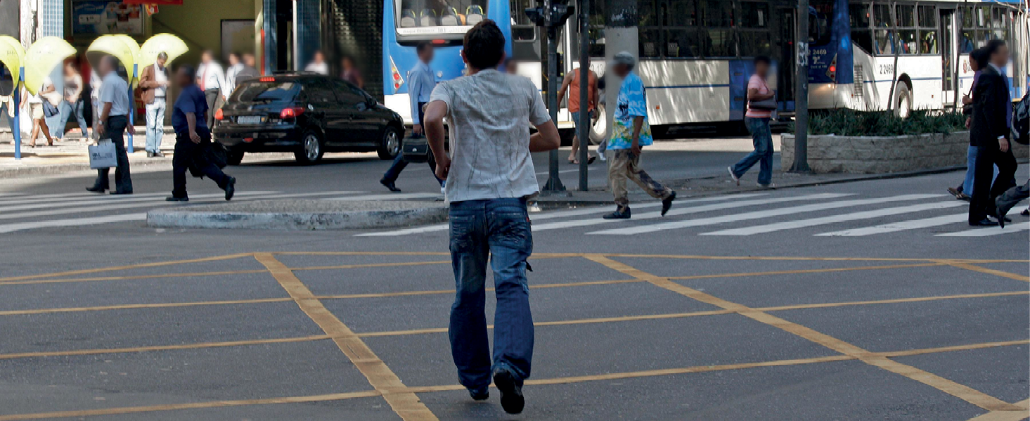 Fotografia. Pedestre atravessando a rua fora da faixa de pedestres.