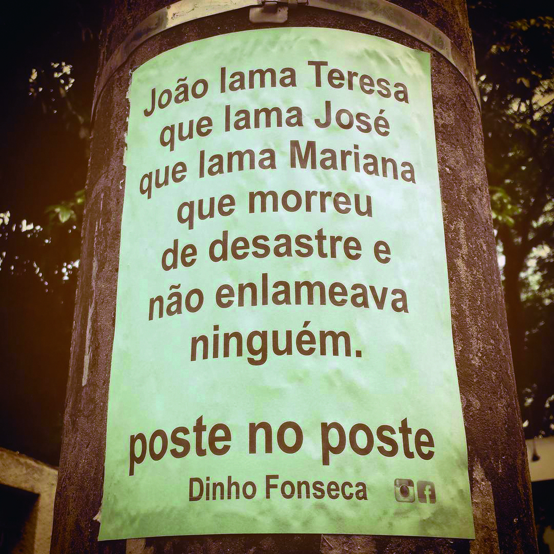 Fotografia. Em tons de sépia, folha clara na vertical, colada em um poste em local aberto. Na folha, texto: JOÃO LAMA TERESA QUE LAMA JOSÉ QUE LAMA MARIANA QUE MORREU DE DESASTRE E NÃO ENLAMEAVA NINGUÉM. POSTE NO POSTE – DINHO FONSECA.