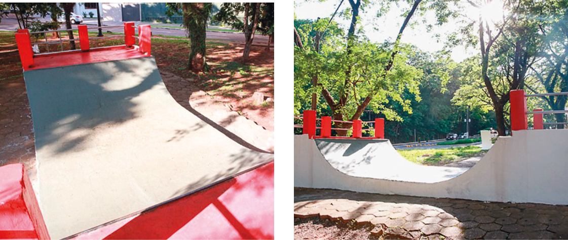 Fotografia. Vista do alto de rampa de skate cinza e, na ponta ao fundo, no alto, as bases vermelhas na vertical e bases cinzas na horizonta. Em segundo plano, chão de terra com gramas esparsas e árvores  de tronco marrom e folhas em verde, vistas parcialmente.
Fotografia. Vista lateral de rampa de skate. Nas laterais superiores, bases vermelhas na vertical e cinza na horizontal. Em segundo plano, árvores de troncos marrons e folhas verdes, com céu em cinza-claro, brilhando a luz solar.