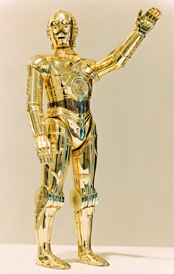 Fotografia de cena de filme. Um robô dourado está em pé, com a cabeça inclinada para o lado e o braço esquerdo estendido para frente e para o alto.