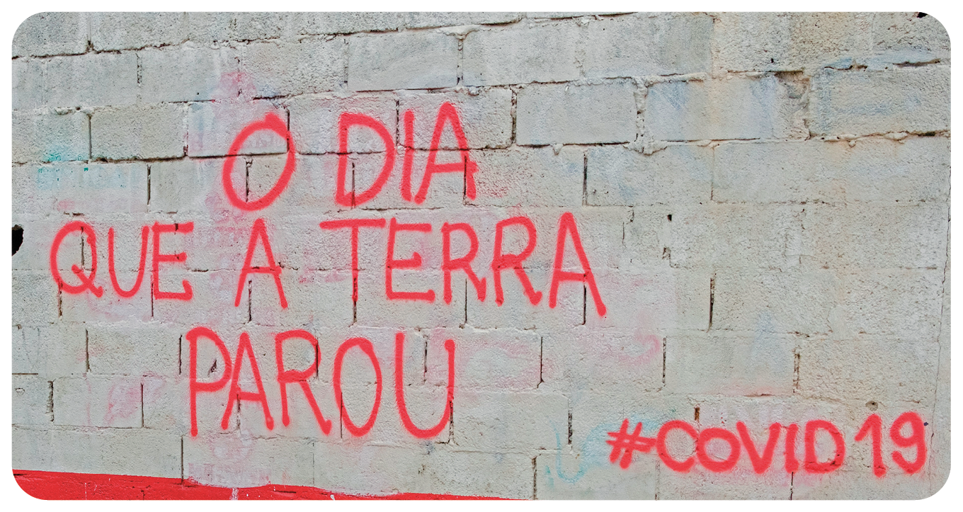 Fotografia. Destaque de uma parede de concreto com a inscrição em vermelho: O DIA QUE A TERRA PAROU #COVID19.
