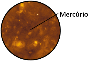 Fotografia. Destaque de uma porção do Sol, fundo amarelado com manchas e um pequeno ponto escuro ao centro, Mercúrio.